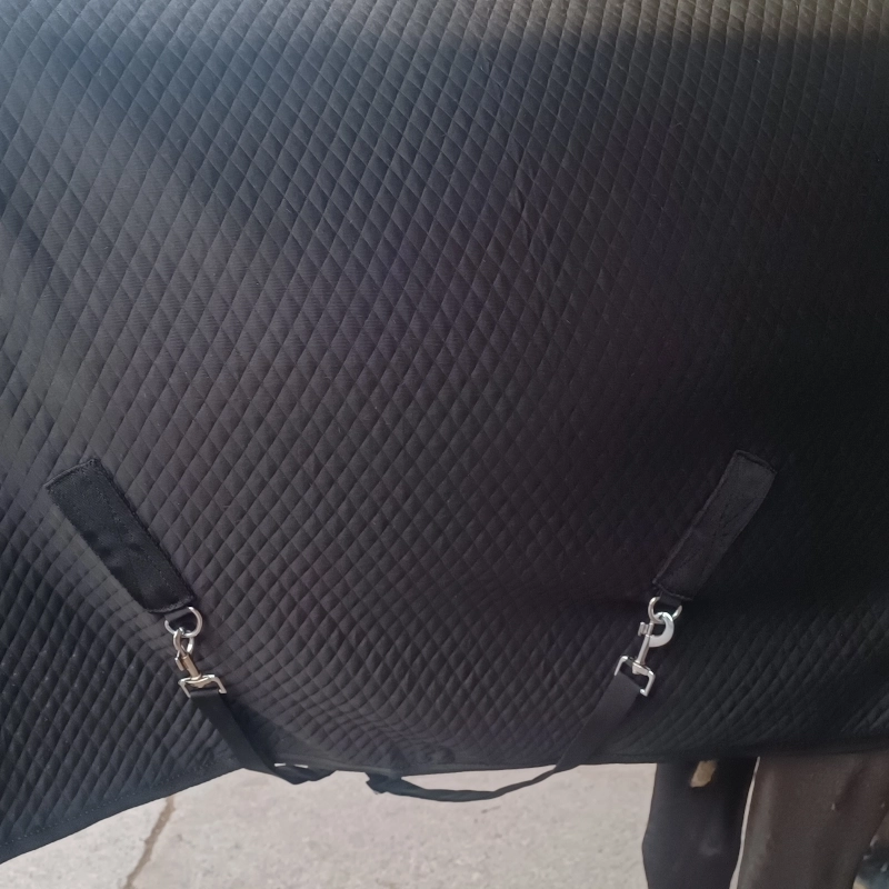 Primer plano de la manta de cuadra de 200gr mostrando el doble cinchuelo cruzado y la textura del tejido acolchado (quilting) en color negro.