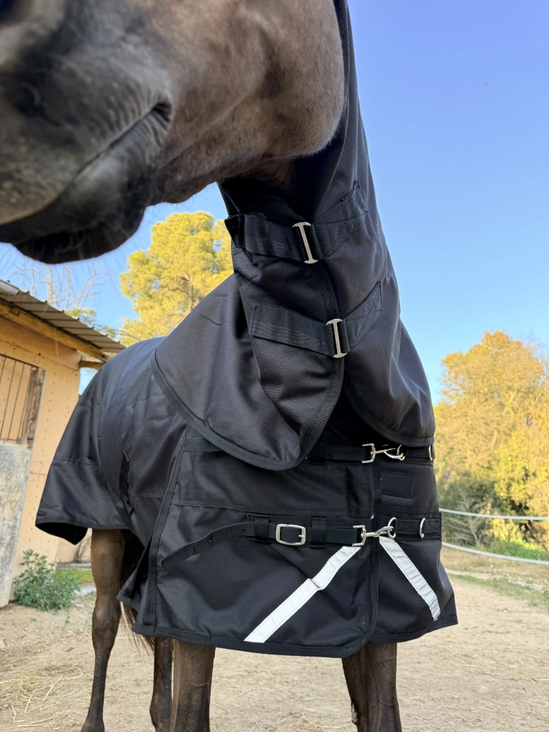 Detalle de los dobles cierres frontales y del cuello en la manta de lluvia 600D, diseñados para un ajuste seguro y evitar la entrada de agua.