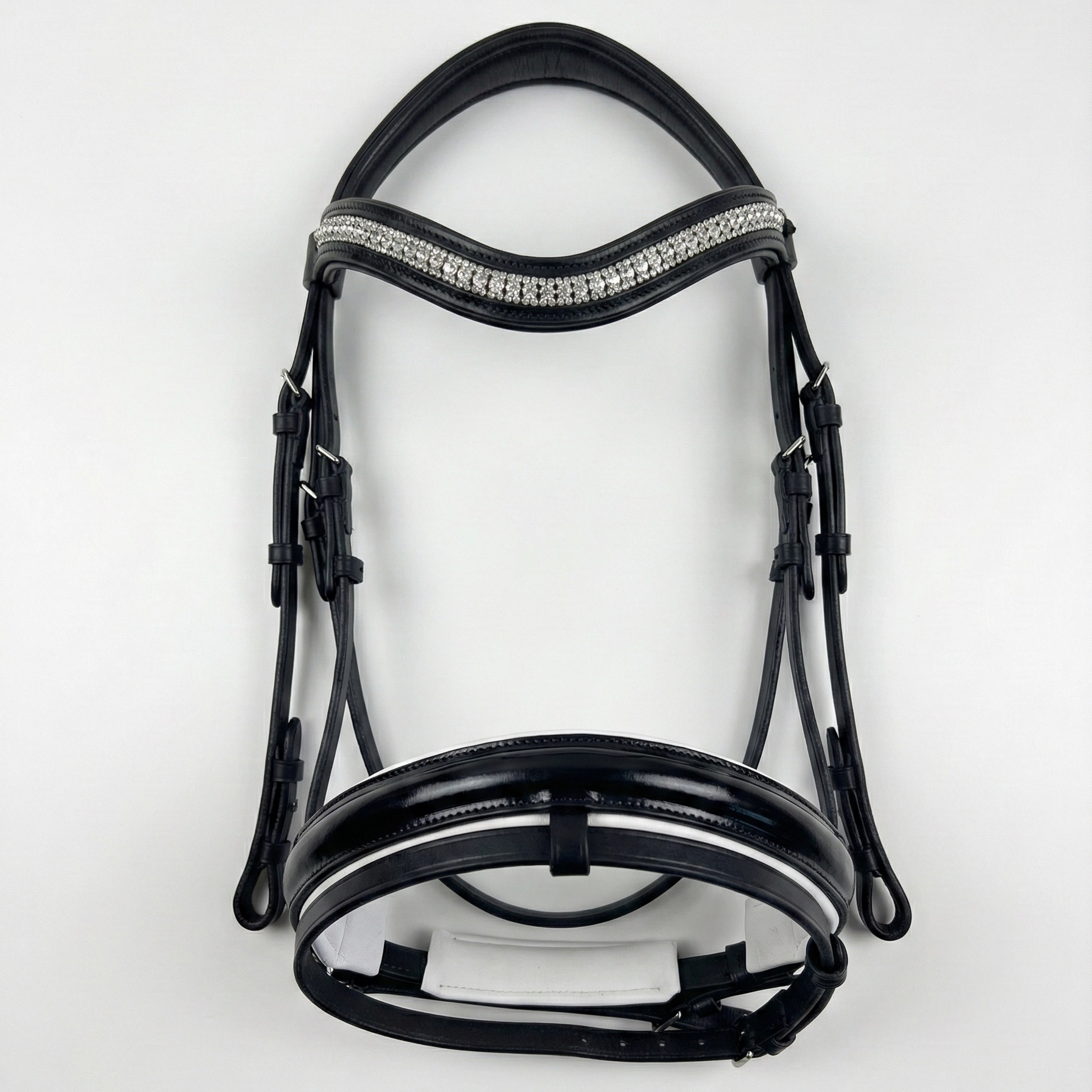 Vista completa del pack de doma, con la cabezada de charol negro equipada con la frontalera de brillantes blancos clásicos para un look de competición.