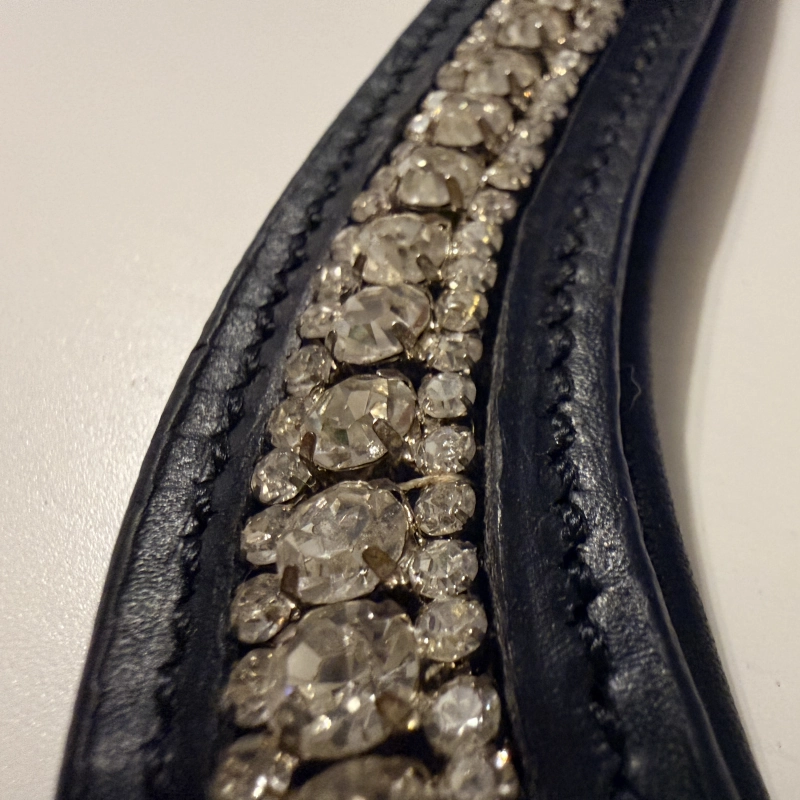 Detalle de los cristales blancos transparentes de 0.3cm y 0.5cm, mostrando su brillo y claridad sobre el cuero negro.