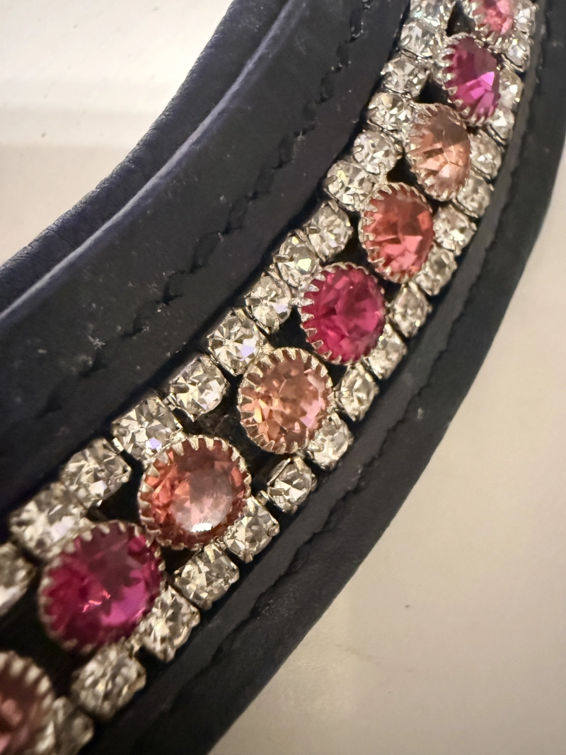 Primer plano de los cristales Tricrystal mostrando la secuencia de tres tonos de rosa (intenso, medio y suave) sobre el cuero negro.