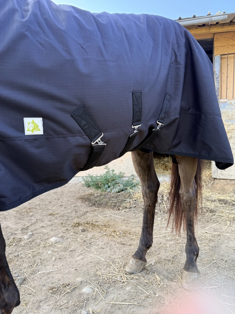 Vista lateral de los tres cinchuelos cruzados que mantienen la manta impermeable 600D fija al cuerpo del caballo, evitando que se gire.