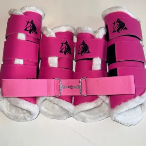 Set de 4 protectores para caballo color rosa enrollados junto a un cinturón elástico rosa con hebilla de bocado y cristales brillantes.